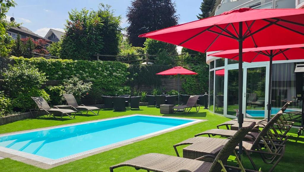 a swimming pool with chairs and umbrellas next to a pool at Göbels Landhotel in Willingen