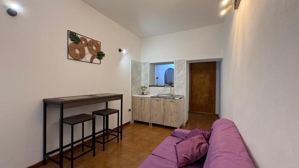 a living room with a purple couch and a kitchen at Casa Vacanze "La Casetta" in Configni