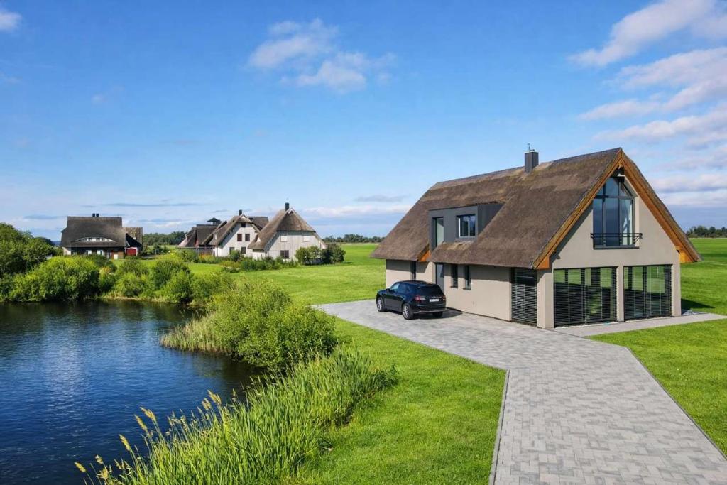 a house with a car parked next to a river at Villa Aurora mit Sauna und Whirlpool in Dranske