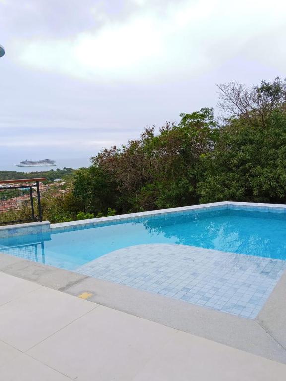 a blue swimming pool with a view of the ocean at Pousada Casa Zoe Búzios in Búzios