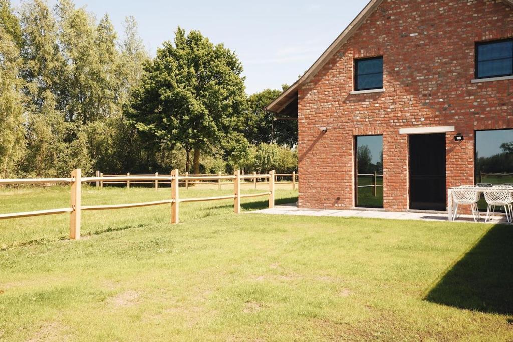 a brick house with a fence next to a field at Huisje Meersen in Maldegem