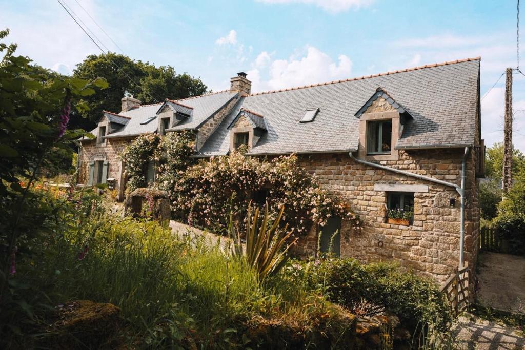 a stone house with a slate roof at La Kahana - cottage paisible, jardin fleuri & permaculture in Lescouët-Gouarec
