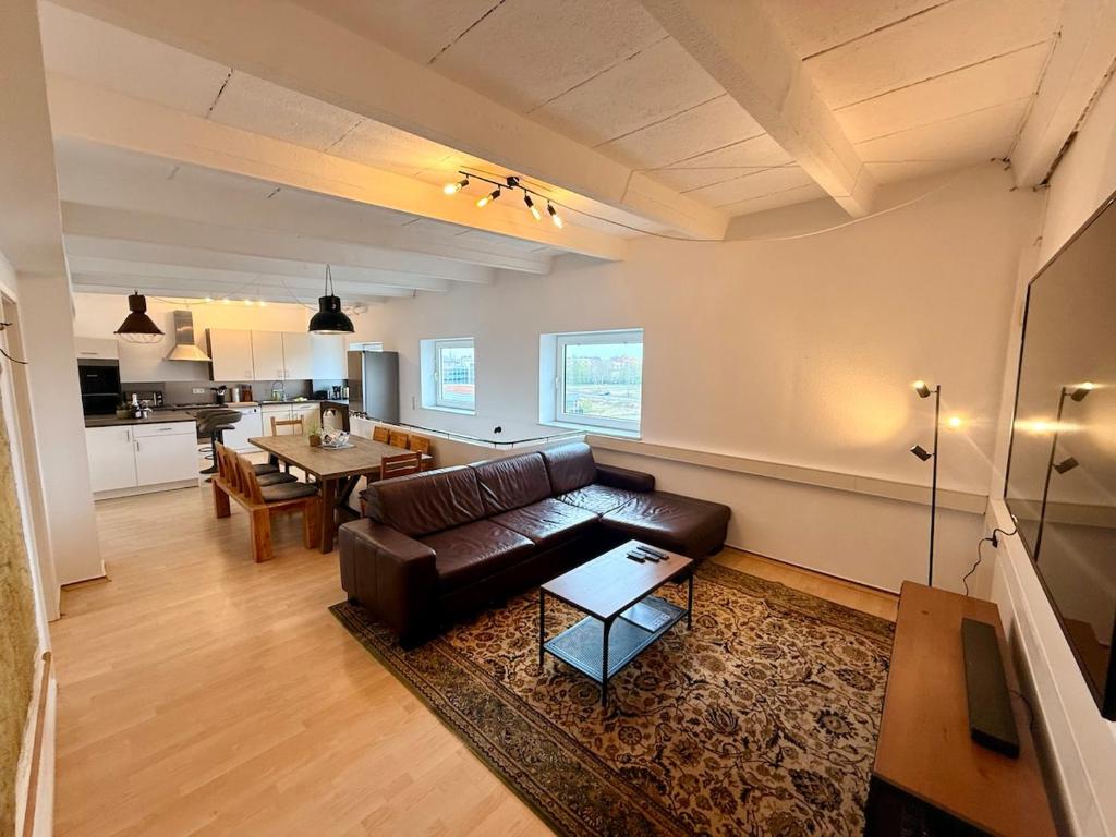 a living room with a leather couch and a table at Spektakuläres Turm-Loft mit Aussicht in Braunschweig
