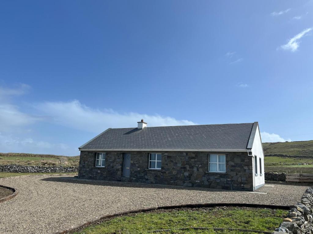 a small stone house with a gravel driveway at Trá Leathan in Doolin