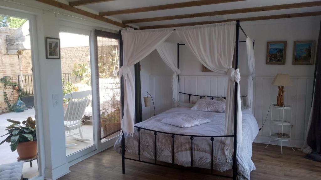 a bedroom with a canopy bed on a porch at une halte templière in Trouillas