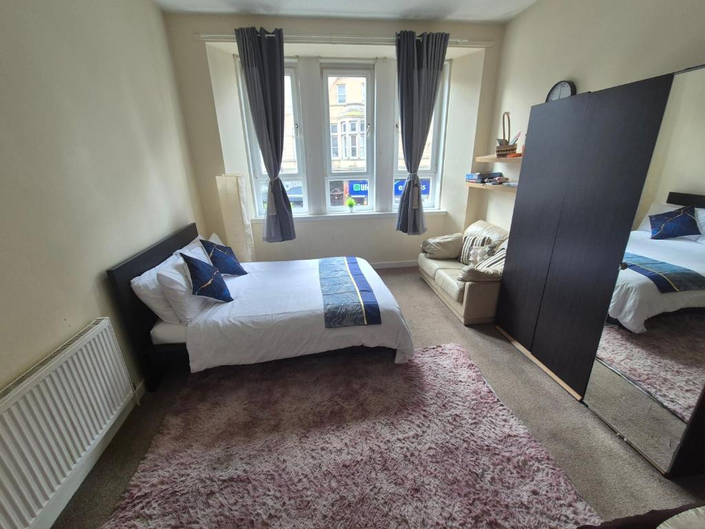 a bedroom with a bed and a couch and a mirror at Cosy and Bright 3-bedroom flat in Glasgow