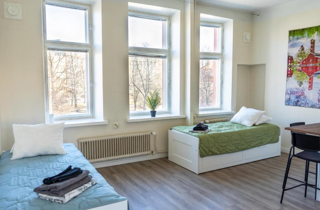 a bedroom with a bed and a desk and windows at Grand Jugend Studio in Kallio in Helsinki