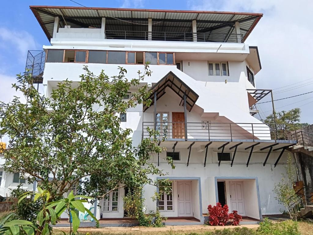 a white house with a tree in front of it at coorg mantion homestay in Madikeri