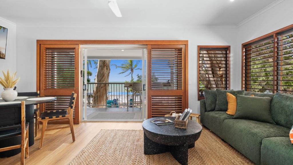 a living room with a green couch and a table at Absolute Beachfront Palm Cove Apt Sleeps 4 in Palm Cove