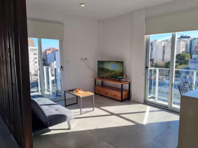 a living room with a couch and a tv and windows at Espectacular departamento en Palermo in Buenos Aires