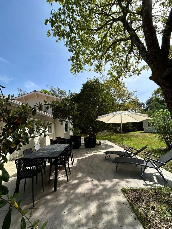 a patio with tables and chairs and an umbrella at La Maison du Square in La Teste-de-Buch