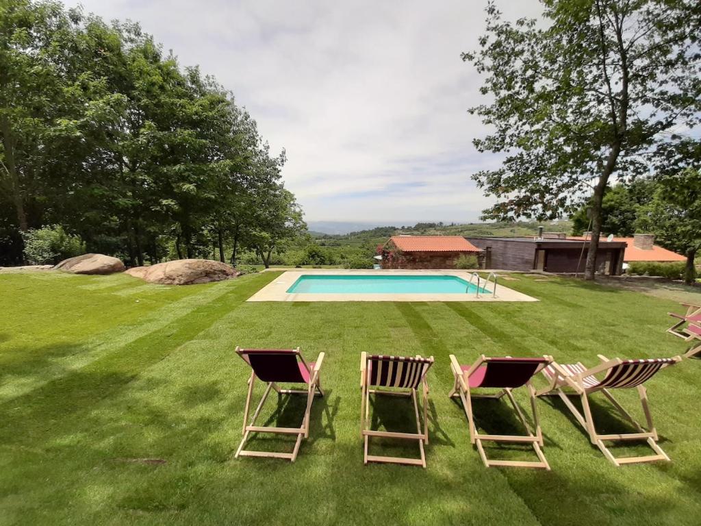 a group of chairs sitting in the grass by a pool at Casa das Rosas in Cimbres