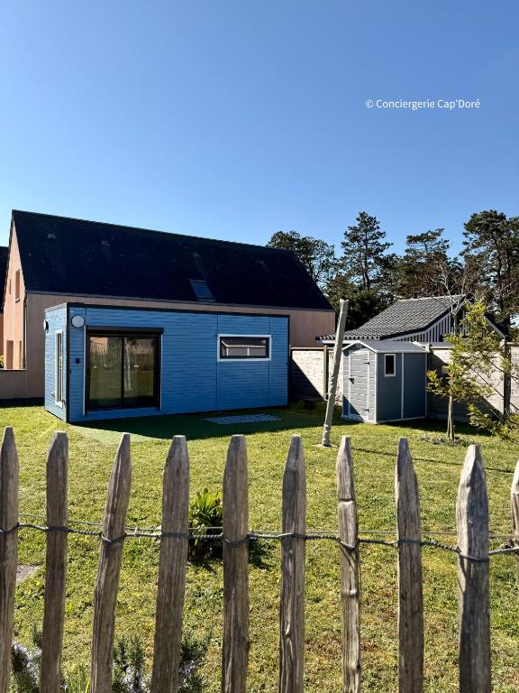 a blue house behind a fence at La Roulotte - Tiny House 150m de la Plage in Portbail