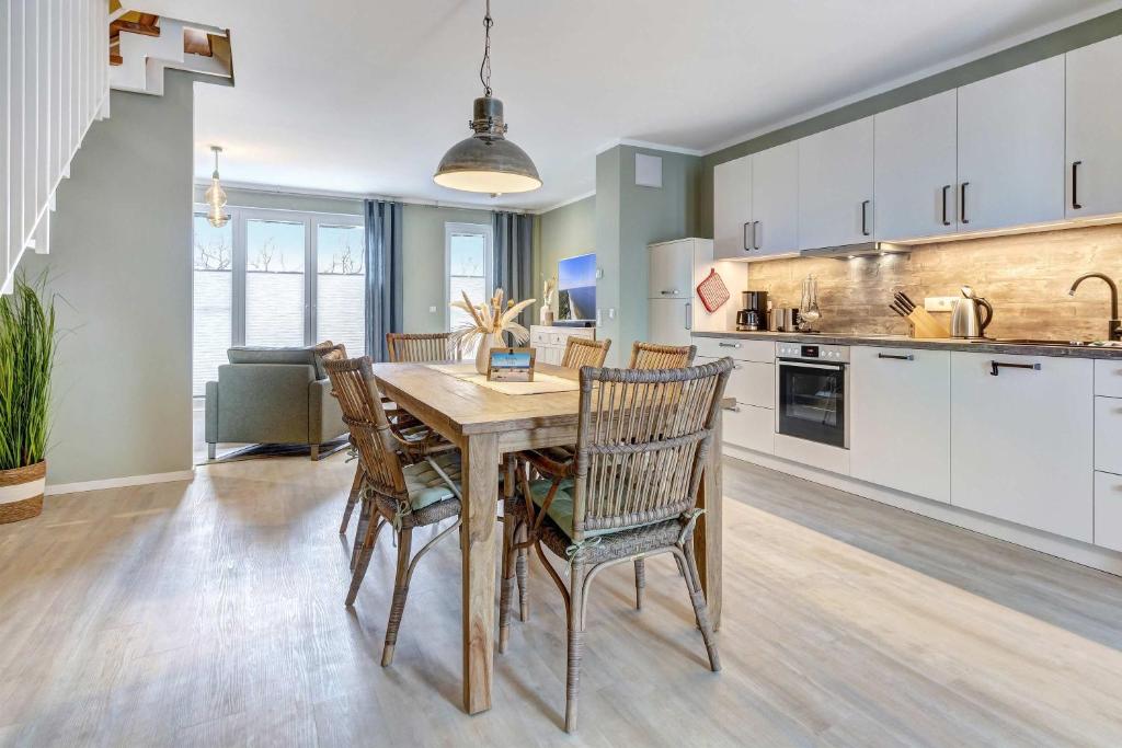a kitchen and dining room with a wooden table and chairs at FeHa Windspiel in Loddin