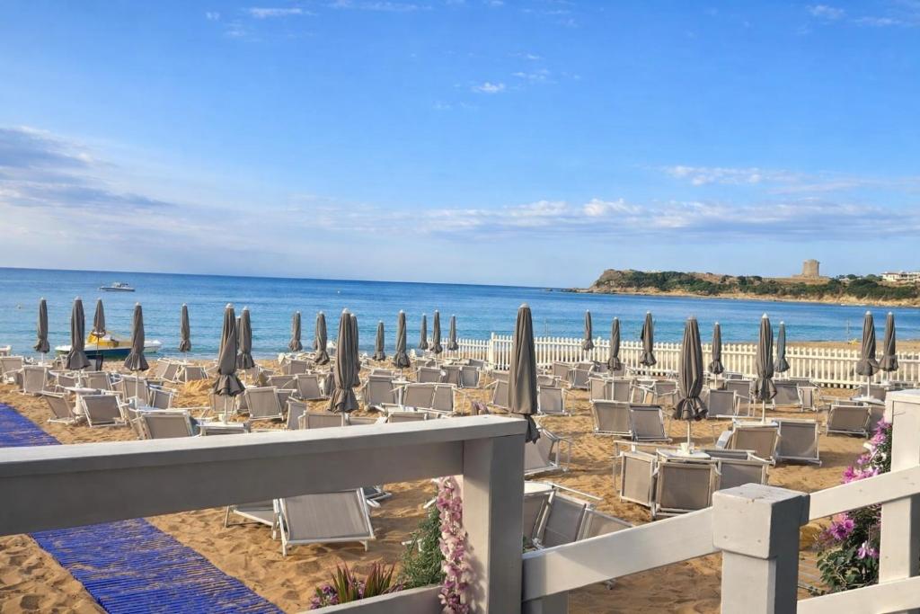 a beach with chairs and umbrellas and the ocean at B&B Capo Rizzuto Armenes in Capo Rizzuto