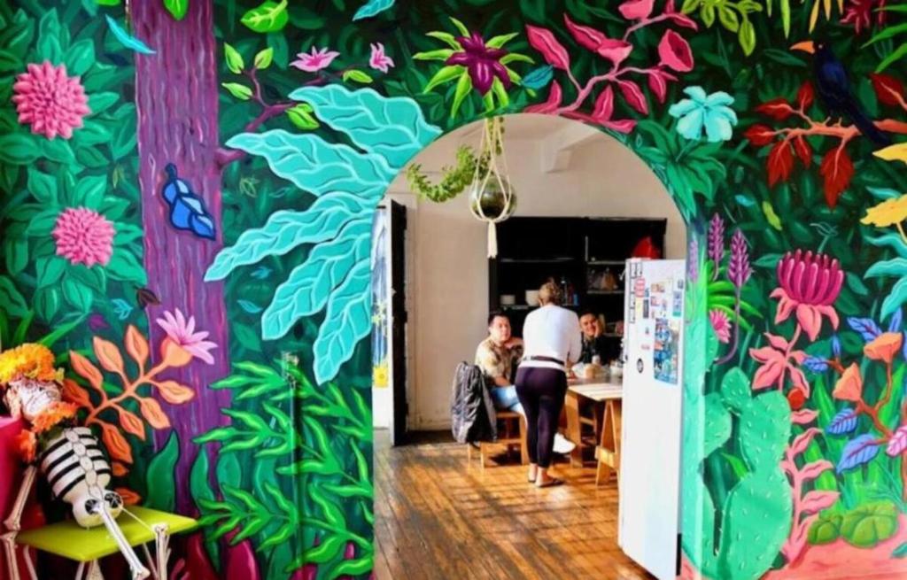 a room with a colorful wall with people sitting at a table at Massiosare El Hostal in Mexico City