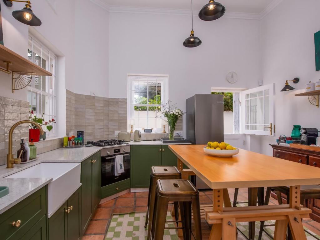 a kitchen with green cabinets and a wooden table at House Erens By Die Bos in Stellenbosch