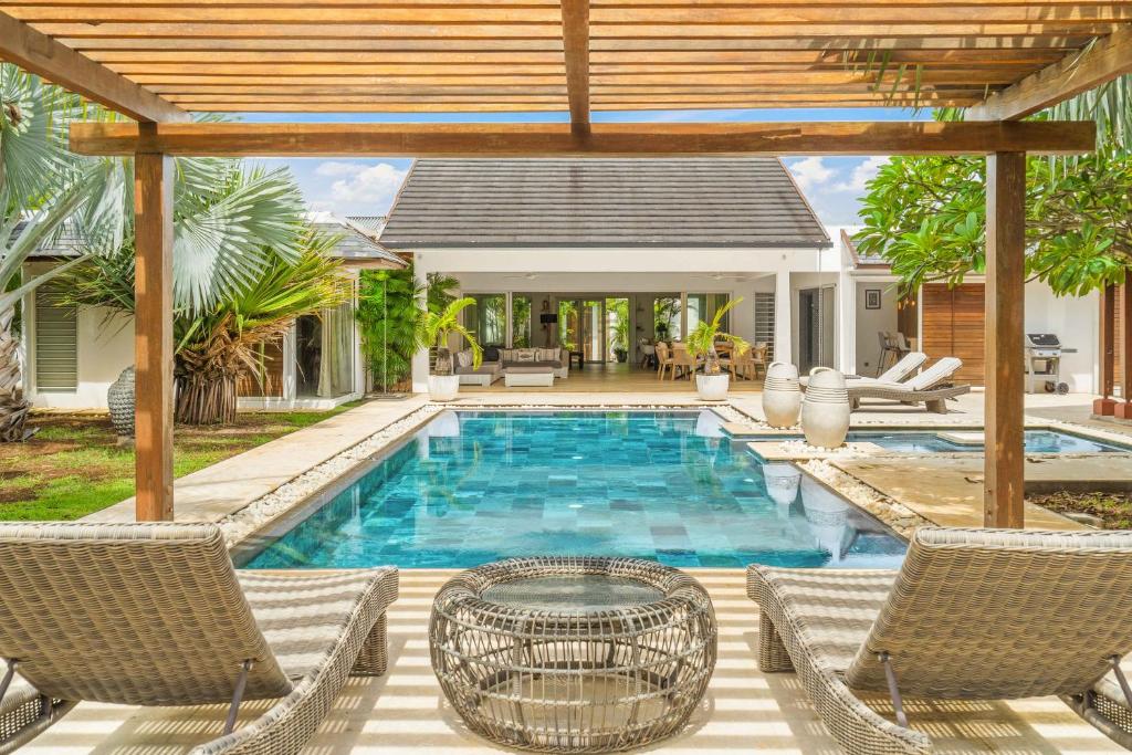 a swimming pool with chairs and a table next to a house at Clos du Littoral by Sealodge Mauritius in Grand-Baie