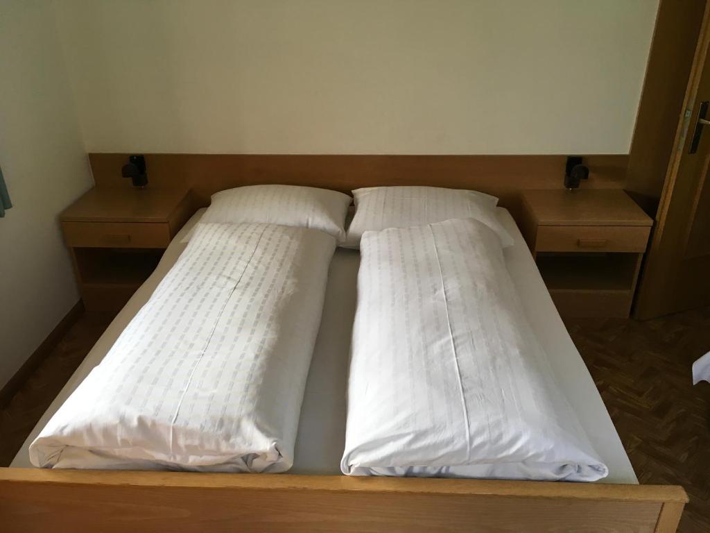 a bed with white pillows on top of it at Fallerhof in Villnoss