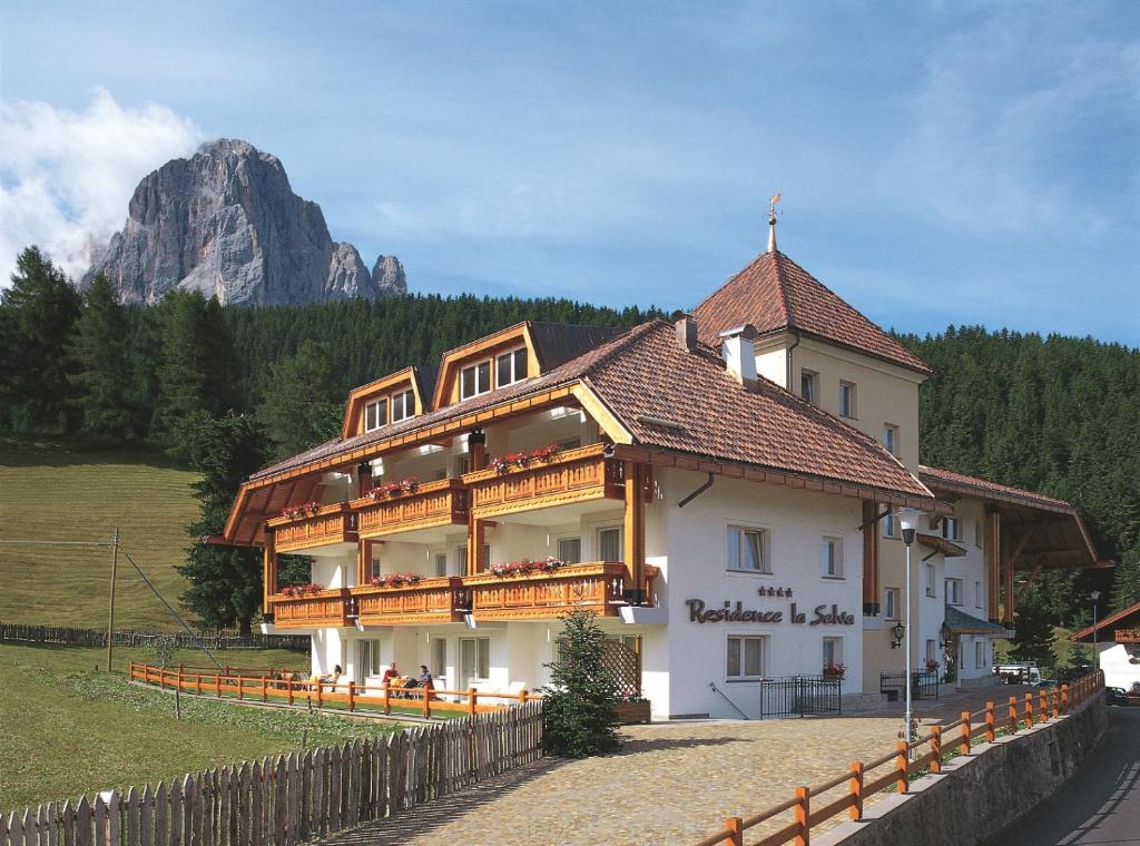 a large building with a mountain in the background at Residence La Selva in Selva di Val Gardena