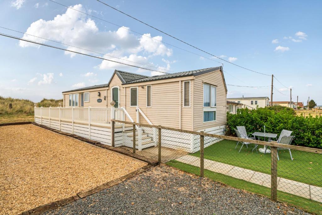 a tiny house with a fence and a yard at Washington Lodge in Heacham