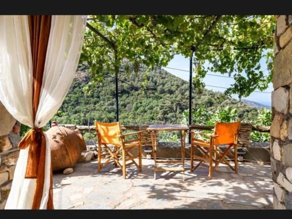 a patio with chairs and a table with a view of a mountain at Mountain Stone Rooms in Mariaí
