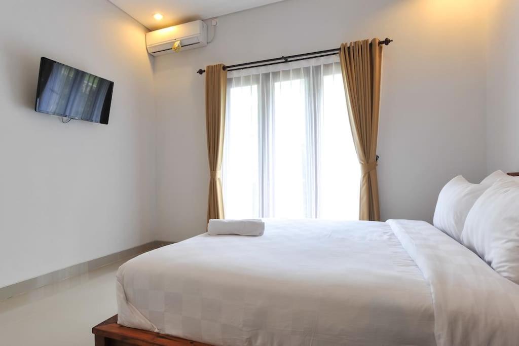 a bedroom with a large white bed and a window at UmahOde Bali in Nusa Dua