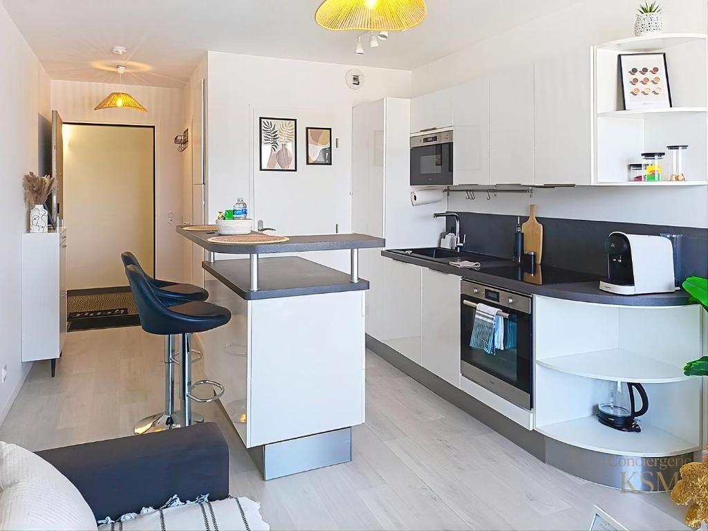 a kitchen with black and white counters and appliances at L'Échappée Verte - T2 avec balcon in Saulx-les-Chartreux