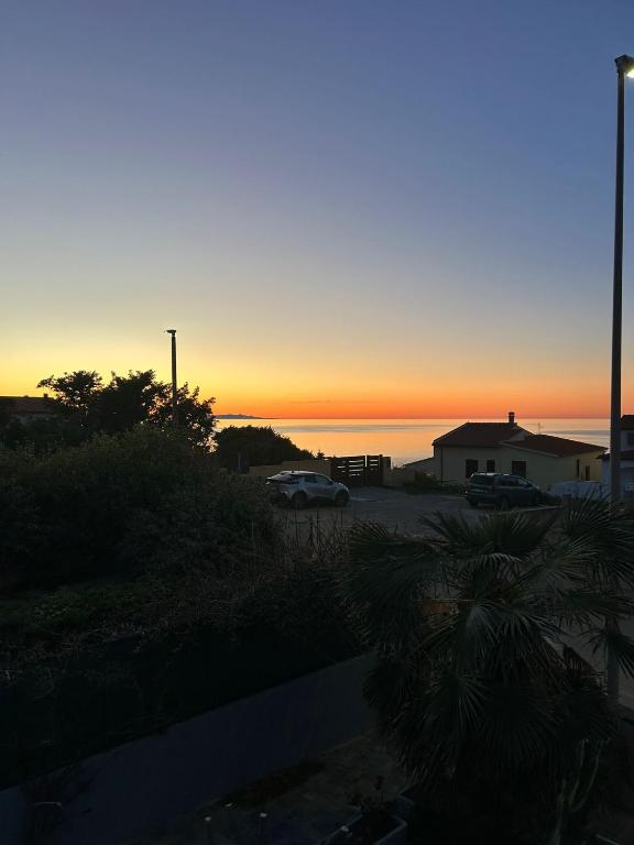 a sunset over the ocean with cars parked in a parking lot at Dimora Vicky - La Ciaccia in Valledoria