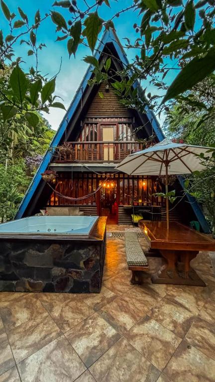 a house with a pool and an umbrella and a table at cabaña master familiar in San Antonio de Pereira