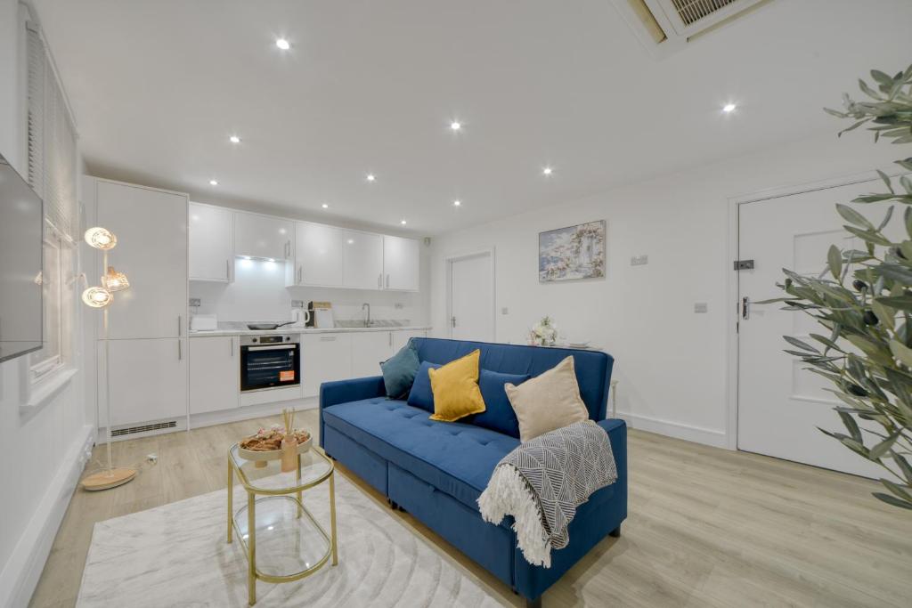 a living room with a blue couch and a kitchen at The Cozy Quarter in Bromley