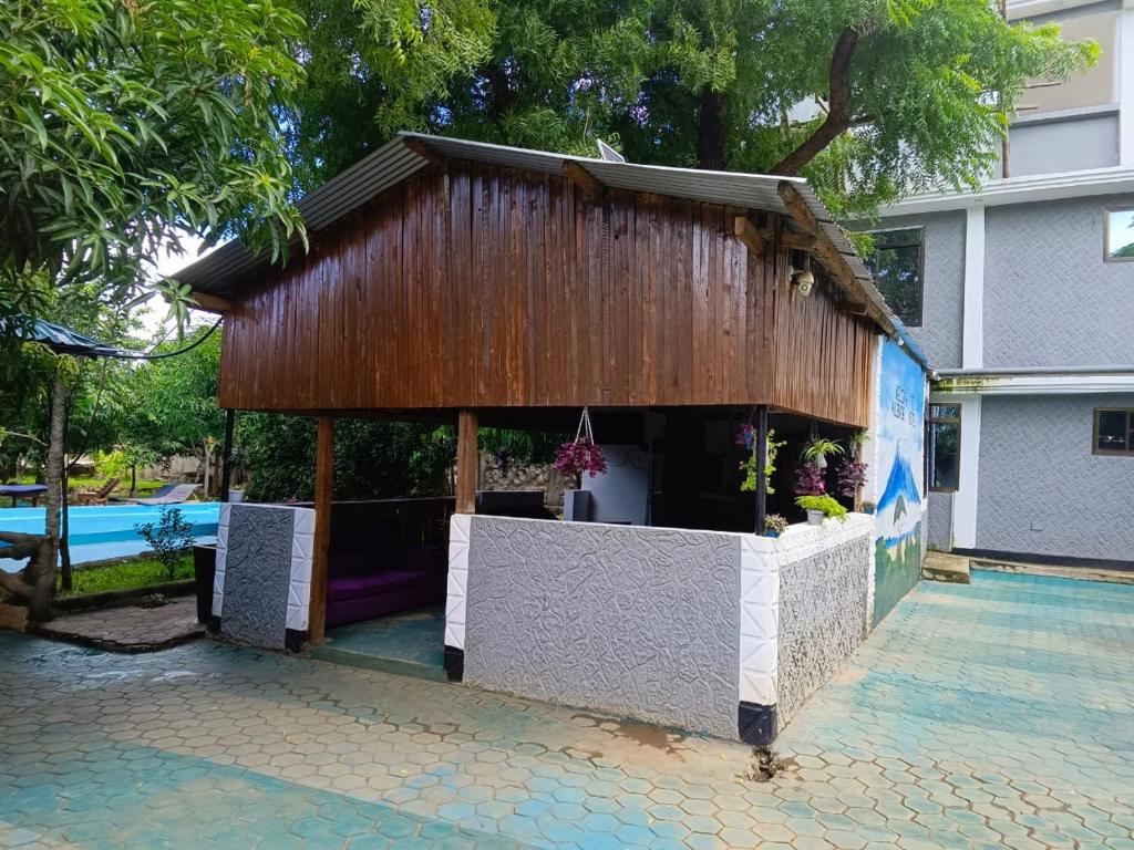 a building with a wooden roof on a patio at Kilibase Hotel in Moshi
