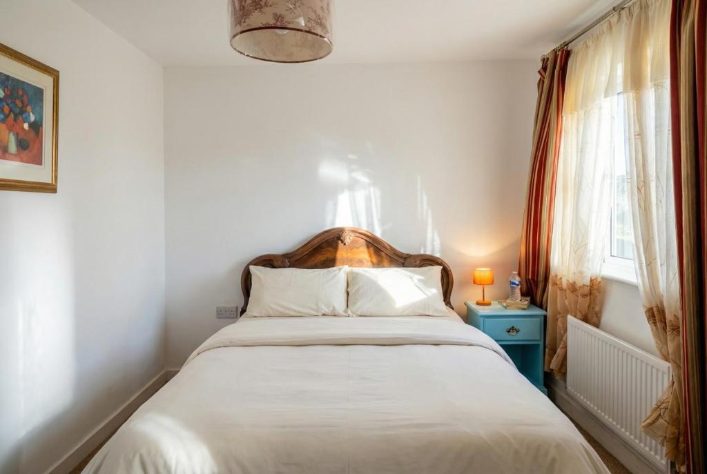 a bedroom with a bed with white sheets and a window at Quiet Three-Bedroom Home in Stewartby with Ensuite and Workspace in Bedford