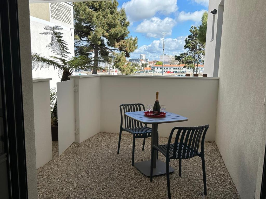 a table and chairs on a balcony with a bottle of wine at Charmante maison vue chenal in Les Sables-d'Olonne