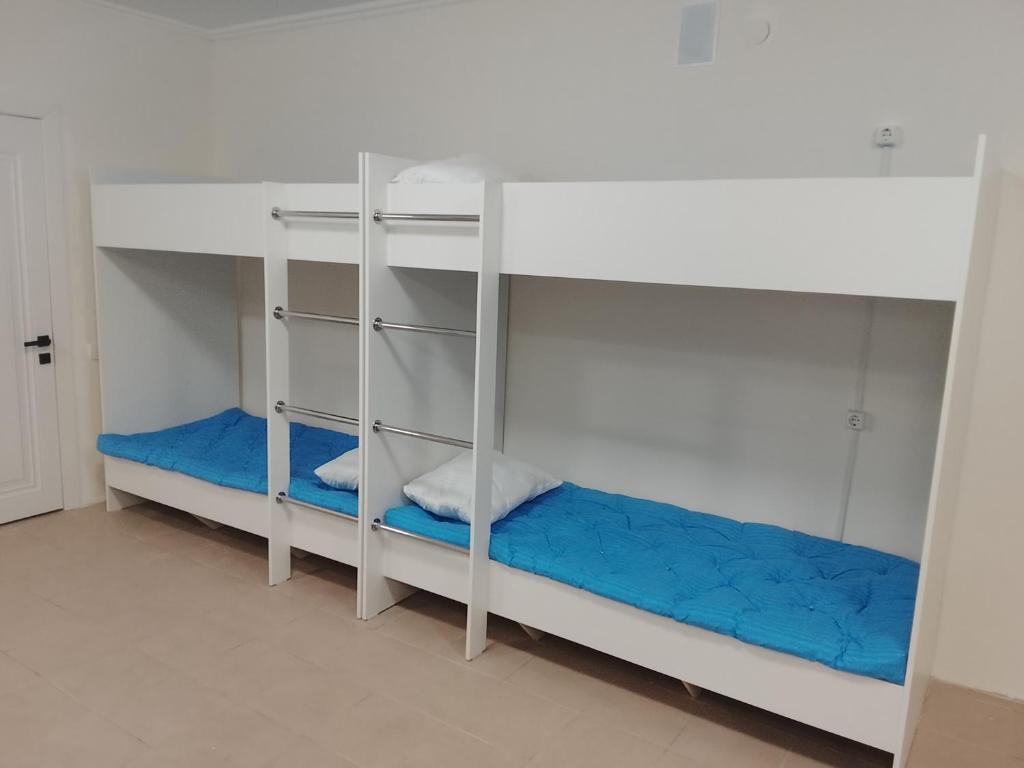 two bunk beds in a room with blue sheets at Atom hostel for men in Astana