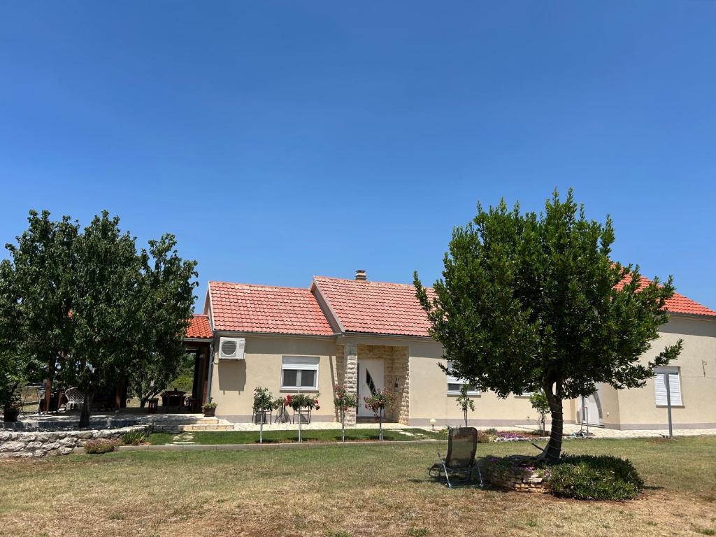 a house with a tree and a chair in the yard at Kuća za odmor - Snowwhite in Smoković