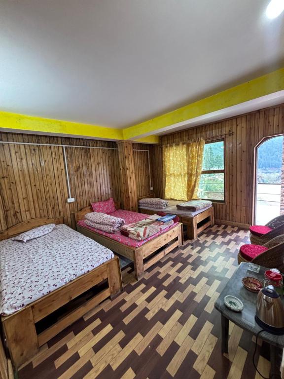 a room with three beds and a table at Shivaay Inn in Lava
