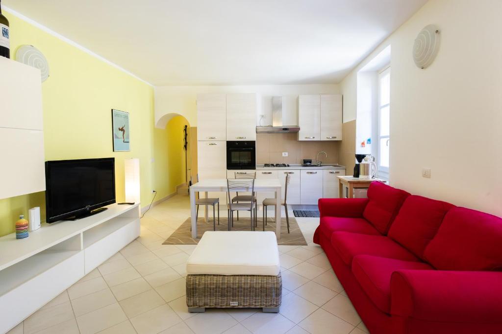 a living room with a red couch and a kitchen at Casa Rosa - hidden Garden with lake view in Fiumelatte