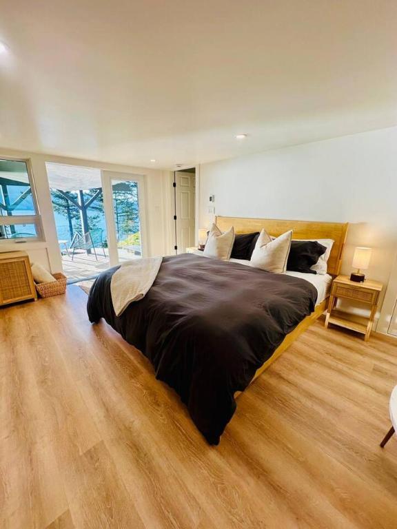 a bedroom with a large bed and a wooden floor at Gorgeous Ocean and Mountain View King Suite in Bowen Island