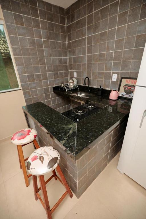 a kitchen with a counter and a stove and two stools at Apartamento 2 Vargem Grande RJ in Rio de Janeiro