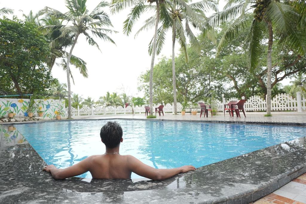a man is sitting in a swimming pool at Siva Bharg Residency in Kovalam