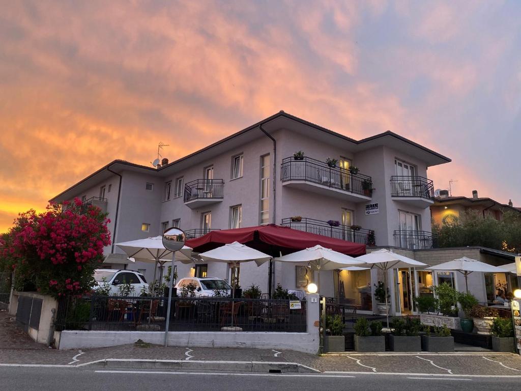 ein Gebäude mit Tischen und Sonnenschirmen davor in der Unterkunft Hotel Marolda in Sirmione