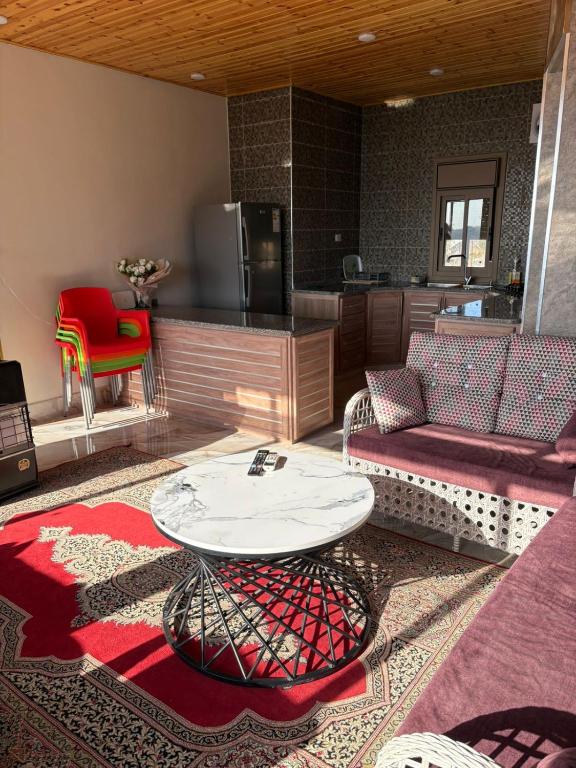 ein Wohnzimmer mit Sofa und Tisch in der Unterkunft Oak Chalet in Umm al Manābī‘