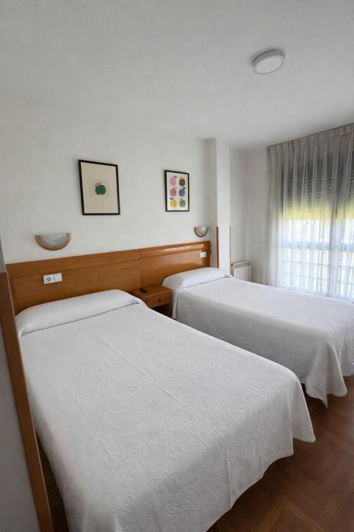 a hotel room with two beds and a window at Pensión Mencia in Lugones