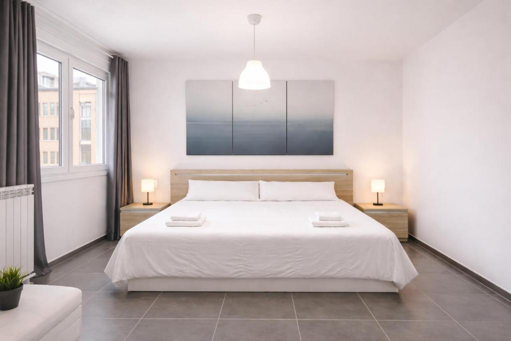 a bedroom with a large white bed with two lamps at Nova Suites Viveiro in Viveiro