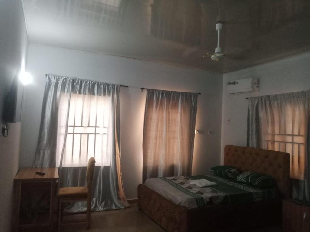 a bedroom with a bed and a desk and windows at Primenest Executive Suites in Gwagwalada