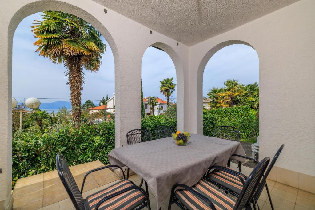 a dining room with a table and chairs and a palm tree at Apartment Renata in Njivice