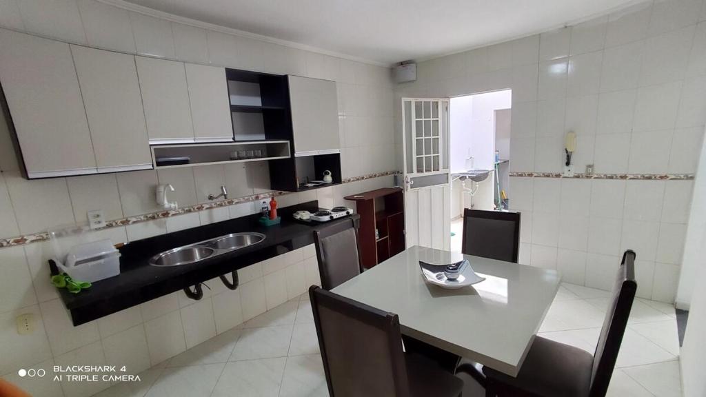 a kitchen with a sink and a table with chairs at Casa confortável a 3km do centro in Petrolina