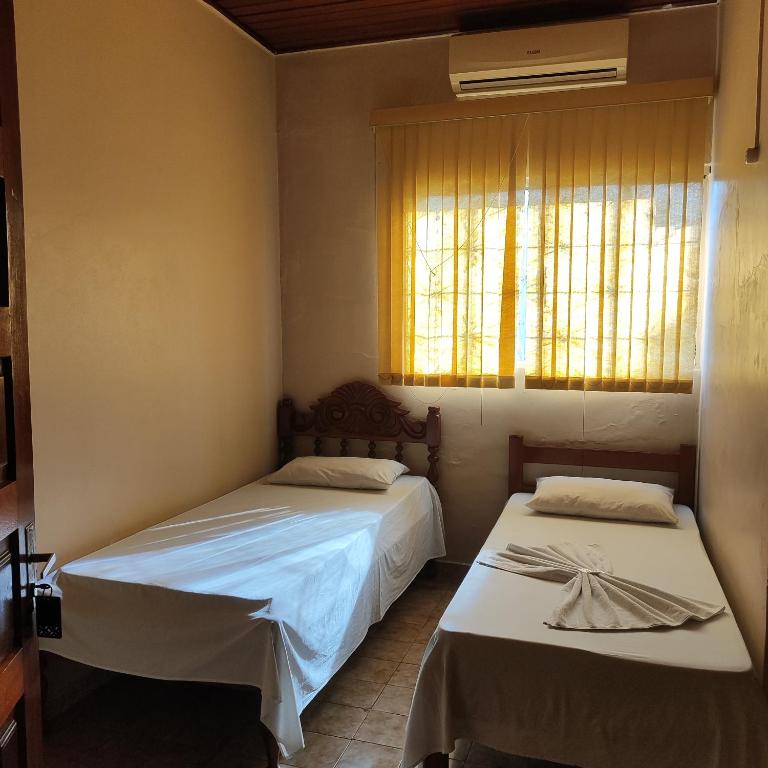 two beds in a small room with a window at Hotel Bela Vista in Costa Marques