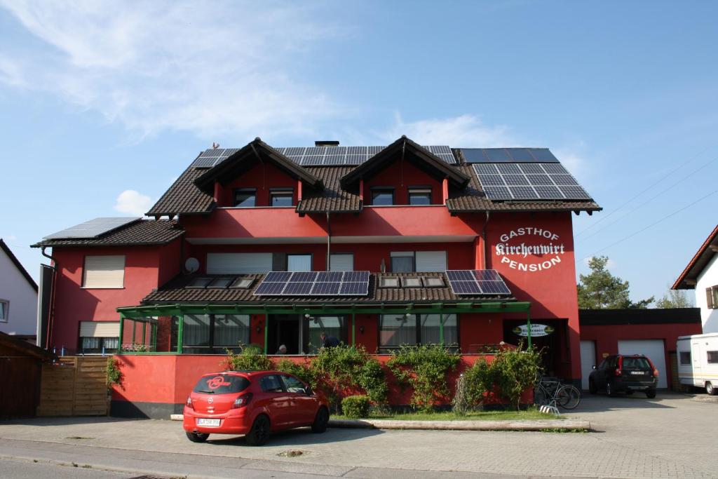 Niederaichbach的住宿－Pension Kirchenwirt，屋顶上设有太阳能电池板的红色建筑